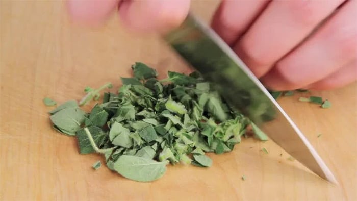 mincing fresh oregano leaves