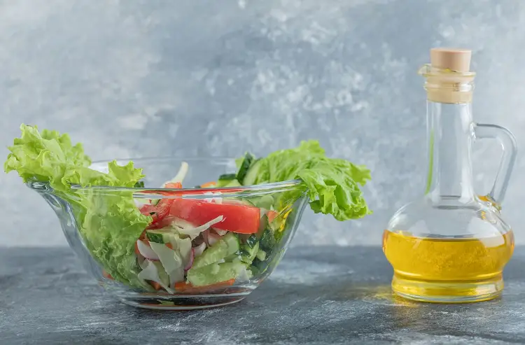 a bowl of green salad and peanut oil bottle